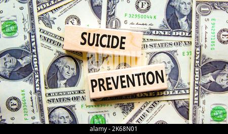 Symbol für die Suizidprävention. Konzept Wörter Selbstmordprävention auf Holzblöcken. Schöner Hintergrund von Dollarscheinen. Psychologische und Selbstmord preven Stockfoto