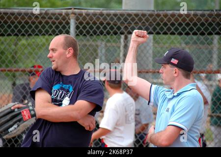 Softball-Schiedsrichter für ASA in den USA bei Spielen, die Anrufe tätigen und im Vorspiel Fledermäuse und Aufstellungen und Regeln überprüfen und solche 3 aus schlagen Stockfoto