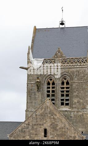 Sainte-Mere-Eglise, FRA, Frankreich - 21. August 2022: Fallschirmjäger-Schaufensterpuppe, die vom Kirchturm hängt Stockfoto