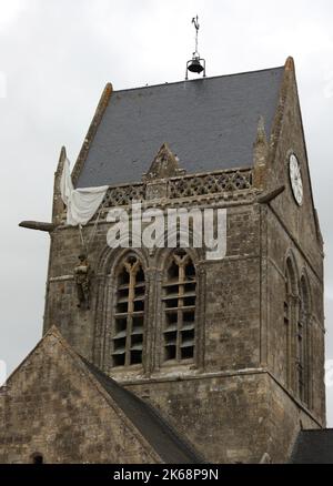 Sainte-Mere-Eglise, FRA, Frankreich - 21. August 2022: Fallschirmjäger-Schaufensterpuppe, die vom Kirchturm hängt Stockfoto