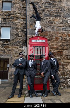 Die akrobatische Gruppe der Black Blues Brothers treten im Dean Village an einer roten Telefonbox auf, Edinburgh, Schottland, Großbritannien Stockfoto