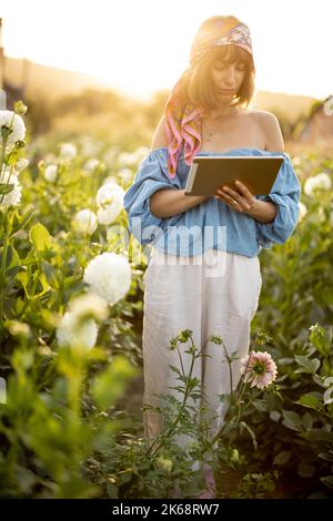 Frau mit einem digitalen Tablet auf der Blumenfarm im Freien Stockfoto