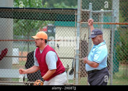 Schwarze männliche Softball-Schiedsrichter in den USA bei Spielen, die Anrufe tätigen, und bei der Überprüfung von Fledermäusen und Aufstellungen und Regeln und solchen Streiks vor dem Spiel Stockfoto