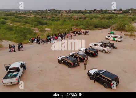 Eagle Pass, USA. 12. Oktober 2022. Asylsuchende Migranten warten am 10. Oktober 2022 auf einen Bus an einem Kontrollpunkt in Eagle Pass, Texas, USA. Busse, die Migranten aus republikanisch geführten Grenzstaaten transportieren, kommen weiterhin in liberalen Bastionen wie New York, Washington, DC und Chicago an und ziehen die US-Migrationskrise in die Augen des Sturms der Partisanenkämpfe vor den Zwischenwahlen im November. Quelle: Nick Wagner/Xinhua/Alamy Live News Stockfoto