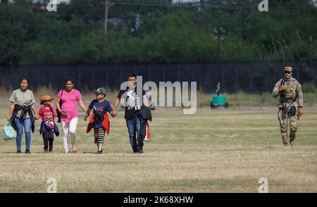 Eagle Pass, USA. 12. Oktober 2022. Am 9. Oktober 2022 begleitet ein texanischer Nationalwächter eine Gruppe von Migranten zu einem Kontrollpunkt in Eagle Pass, Texas, USA. Busse, die Migranten aus republikanisch geführten Grenzstaaten transportieren, kommen weiterhin in liberalen Bastionen wie New York, Washington, DC und Chicago an und ziehen die US-Migrationskrise in die Augen des Sturms der Partisanenkämpfe vor den Zwischenwahlen im November. Quelle: Nick Wagner/Xinhua/Alamy Live News Stockfoto