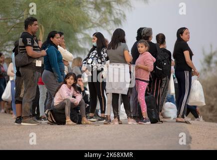 Eagle Pass, USA. 12. Oktober 2022. Asylsuchende Migranten warten am 10. Oktober 2022 auf einen Bus an einem Kontrollpunkt in Eagle Pass, Texas, USA. Busse, die Migranten aus republikanisch geführten Grenzstaaten transportieren, kommen weiterhin in liberalen Bastionen wie New York, Washington, DC und Chicago an und ziehen die US-Migrationskrise in die Augen des Sturms der Partisanenkämpfe vor den Zwischenwahlen im November. Quelle: Nick Wagner/Xinhua/Alamy Live News Stockfoto