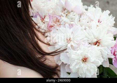 Großes Bouquet von Pfingstrosen in weiblichen Händen. Nicht erkennbare Frau mit einem Strauß rosa Pfingstrosen Stockfoto