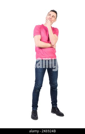 Positiver Mann im lässigen Outfit, der Kinn berührt und denkt Stockfoto
