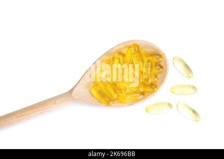 Stapel von Kapseln Omega 3 in Holzlöffel isoliert auf weißem Hintergrund. Softgels, Tabletten für Haut, Gesundheit, Behandlung von Krankheiten. Gesundheit, Ernährung, Herz Stockfoto