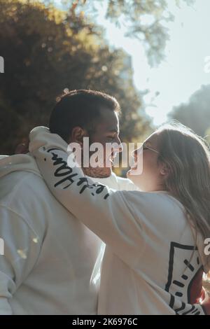 Ein flacher Fokus eines glücklichen lächelnden Paares, das sich umarmt und in einem Park anschaut Stockfoto
