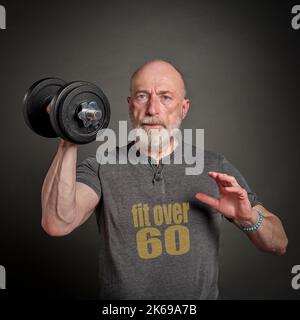 Der kahle und bärtige Mann mit T-Shirt mit über 60 Texten trainiert mit einer schweren Hantel, einem aktiven Senioren- und Fitnesskonzept Stockfoto