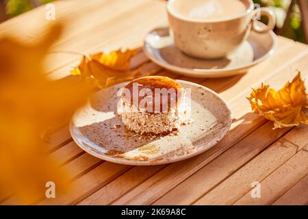 Ästhetische Herbst gesunde Karotten Dessert mit Agavensirup. Kuchen mit einer Tasse Kaffee unter harten Schatten draußen. Gesundes Frühstück. Stockfoto