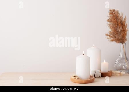 Dekoration mit Kerzen und Blumen über der weißen Wand. Interior Design Konzept. Nahaufnahme, Kopierbereich Stockfoto