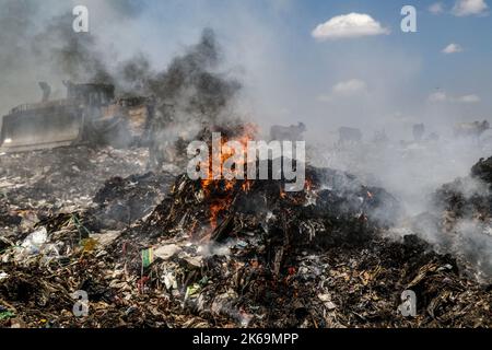 Nairobi, Kenia. 11. Oktober 2022. Rauch steigt aus brennendem Müll auf dem Dandora-Mülldeponie. Es gibt Bedenken, dass Rauch aus brennendem Müll giftige Chemikalien emittiert, die Umwelt- und Gesundheitsprobleme verursachen. Die Plünderer und die an Deponien grenzenden Gemeinden, in denen Abfälle offen verbrannt werden, sind stark betroffen. (Bild: © James Wakibia/SOPA Images via ZUMA Press Wire) Stockfoto