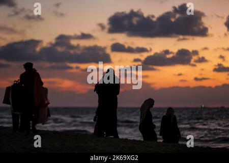 12. Oktober 2022, Gaza-Stadt, der Gazastreifen, Palästina: Palästinenser sitzen während des Sonnenuntergangs westlich des zentralen Gazastreifens am Ufer des Mittelmeers. (Bild: © Mahmoud Issa/Quds Net News via ZUMA Press Wire) Stockfoto