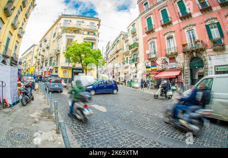 April 04 2022 - Neapel Italien - die überfüllte Straße eines Morgens mit vielen Motorroller und Leuten, die an alten bunten Gebäuden vorbeilaufen, um zu arbeiten Stockfoto