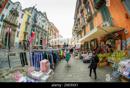 April 04 2022 - Neapel Italien - die überfüllte Straße eines Morgens mit vielen Motorroller und Leuten, die an alten bunten Gebäuden vorbeilaufen, um zu arbeiten Stockfoto