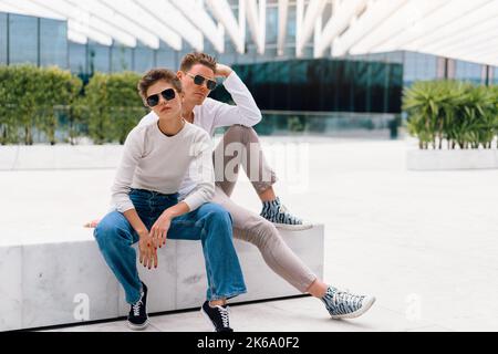 Junges Paar mit Problemen in ihrer Beziehung. Mann und Frau Freunde in Sonnenbrillen Sitzbank in der Stadt unglückliche Emotionen. Beziehungsproblem. Stockfoto