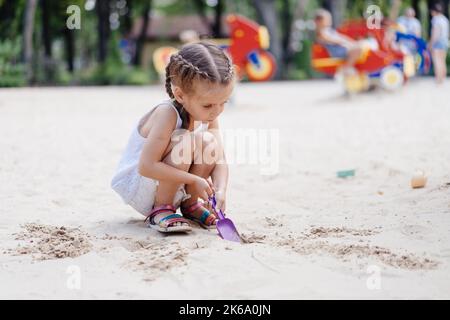 Kleines Mädchen Spielt Sandbox Spielplatz Graben Sand Schaufel Gebäude Sandfigur Sommertag. Kaukasische weibliche Kind 5 Jahre haben Spaß im Freien Stockfoto