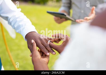 Nahaufnahme eines afroamerikanischen Paares, das während der Hochzeit den Ring legt Stockfoto