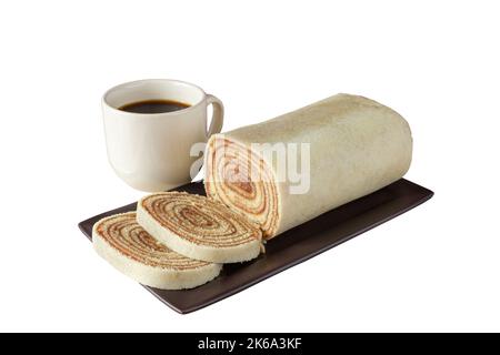 Geschnittenes Bolo de rolo auf einem braunen Teller neben einer Tasse Kaffee (weißer Hintergrund). Stockfoto