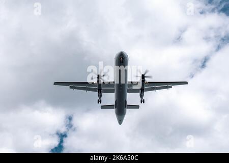 Kleines Propellerflugzeug, das vor der Landung über den Kopf fliegt. Der Boden des Flugzeugs am Himmel Stockfoto