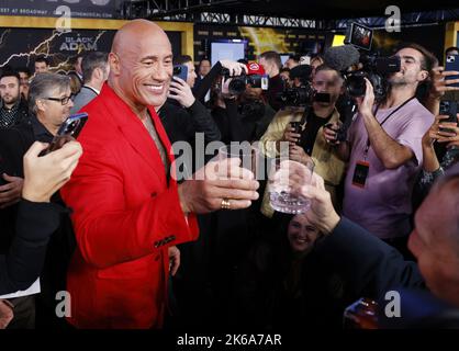 New York, Usa. 12. Oktober 2022. Dwayne 'The Rock' Johnson und das Mitglied der Wrestling Hall of Fame und Fotograf George Napolitano heben eine Brille, die mit Dwayne 'The Rock' Johnsons Marke Tequila gefüllt ist, als Johnson am 12. Oktober auf dem roten Teppich für die New Yorker Premiere von DC „Black Adam“ im AMC Empire 25 auf dem Times Square ankommt, 2022 in New York City. Foto von John Angelillo/UPI Credit: UPI/Alamy Live News Stockfoto