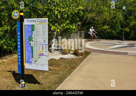 Harbourwalk-Schild für die Stadt Punta Gorda mit einer Karte mit Fahrradfahrern, die die Wege im Trabue Park auf dem Harbourwalk in Punta Gorda, Florida, genießen Stockfoto