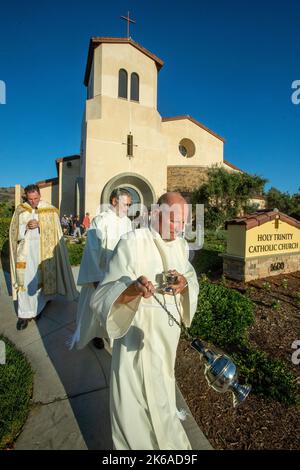Begleitet von Diakone begleitet der Priester einer katholischen Kirche in Südkalifornien eine Prozession. Beachten Sie das Räuchergefäß zum Verbrennen von Weihrauch. Stockfoto