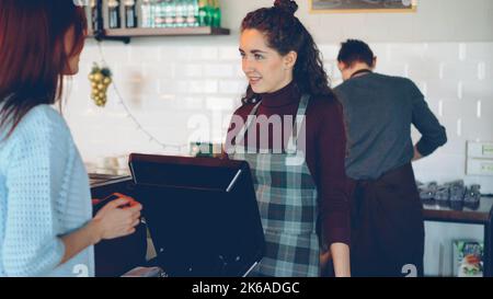 Junge Kundin kauft Kaffee zum Mitnehmen in einem modernen Café. Stockfoto