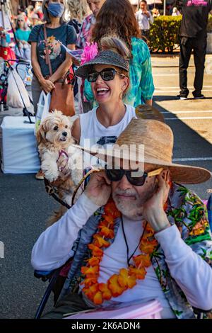 Ein überschwänglicher Elvis Presley-Fan streicht ihren Hund bei einer Unterhaltung im Elvis Presley-Look in Fullerton, CA, während ein älterer Zuschauer seine Ohren verschließt Stockfoto