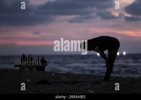 Gaza, Palästina. 12. Oktober 2022. Ein Palästinenser betet während des Sonnenuntergangs westlich des zentralen Gazastreifens am Ufer des Mittelmeers. (Foto von Mahmoud Issa/SOPA Images/Sipa USA) Quelle: SIPA USA/Alamy Live News Stockfoto