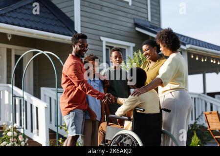 Porträt einer großen afroamerikanischen Familie mit Person im Rollstuhl, die im Freien bei Haus steht Stockfoto