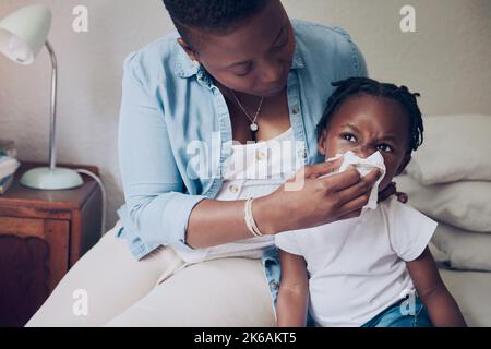 Sie brauchen nur etwas mütterliche Liebe. Eine junge Mutter hilft ihrer Tochter, ihre Nase zu Hause zu blasen. Stockfoto