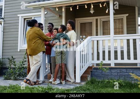 In voller Länge Porträt der glücklichen schwarzen Familie umarmt, während auf der Veranda des neuen Hauses stehen, kopieren Raum Stockfoto