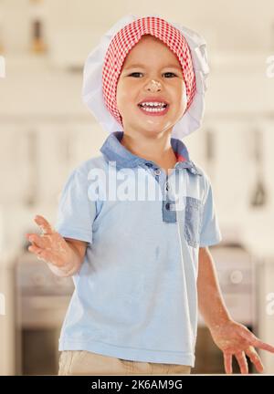 Spaß mit Mehl. Ein kleiner Junge glücklich mit Mehl und Teig aus dem Backen bedeckt. Stockfoto