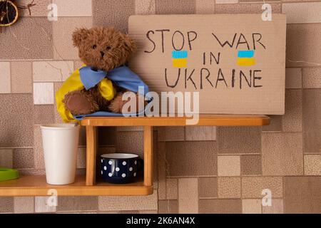 Stoppen Sie den Krieg in der Ukraine je geschrieben auf einem Schild, das auf Regal in der Ukraine in der Nähe eines Teddybären steht. Frieden in der Ukraine. Protest Stockfoto