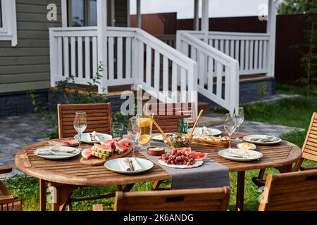 Hintergrundbild von Holz Esstisch Set für Sommerparty im Freien mit frischen Früchten und Beeren Stockfoto
