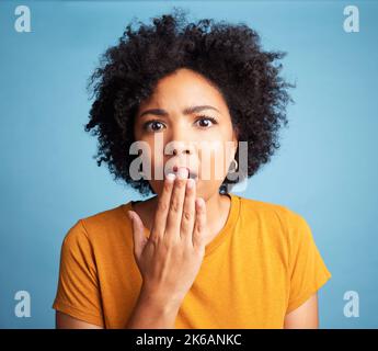 Auf keinen Fall. Eine attraktive junge Frau, die allein vor blauem Hintergrund im Studio steht und überrascht aussieht. Stockfoto