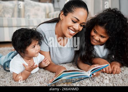 Die beste Zeit des Tages. Eine Mutter liest ihren Töchtern vor. Stockfoto