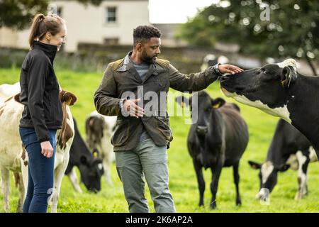 NUR FÜR REDAKTIONELLE ZWECKE JB Gill (Mitte) mit Jo Lawrence, Senior Manager Arla Foods, als er mit Arla Cravendale auf einer Farm in den Yorkshire Dales zusammenarbeitet, um die Veröffentlichung von „Everybody's Free A-Cowppella Style“ anzukündigen, der die Marke Free to Graze Standard und ein breiteres PFLEGEPROGRAMM feiert. Ausgabedatum: Donnerstag, 13. Oktober 2022. Stockfoto