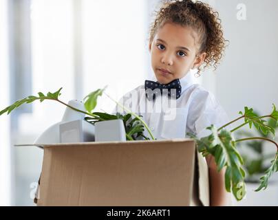 Nun, ich glaube, ich bin hier draußen. Ein entzückendes kleines Mädchen, das als Geschäftsfrau gekleidet war und nach der Entlassung eine Schachtel mit ihren Habseligkeiten in der Hand hielt. Stockfoto