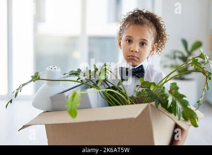 Ich wurde gefeuert. Ein entzückendes kleines Mädchen, das als Geschäftsfrau gekleidet war und nach der Entlassung eine Schachtel mit ihren Habseligkeiten in der Hand hielt. Stockfoto