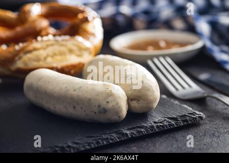 Traditionelle bayerische Weißwürste auf Schneidebrett und Brezeln. Stockfoto