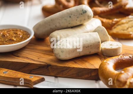 Traditionelle bayerische Weißwürste auf Schneidebrett und Brezeln. Stockfoto