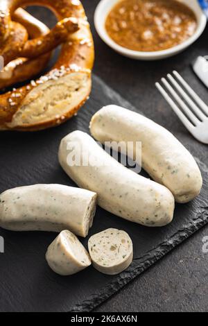 Traditionelle bayerische Weißwürste auf Schneidebrett und Brezeln. Stockfoto