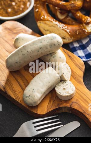 Traditionelle bayerische Weißwürste auf Schneidebrett und Brezeln. Stockfoto