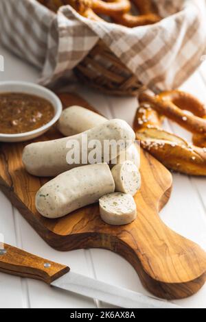 Traditionelle bayerische Weißwürste auf Schneidebrett und Brezeln. Stockfoto