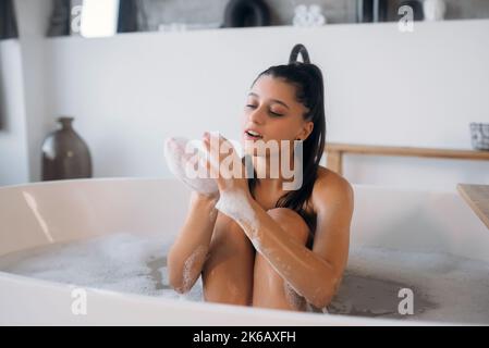 Die junge Frau genießt den Schaum beim Baden Stockfoto