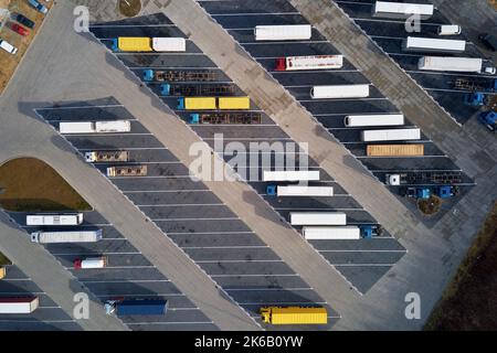 Draufsicht auf Sattelschlepper, die auf dem Parkplatz am Logistiklager auf die Verladung warten. Luftaufnahme von LKW-Anhängern auf dem Rastplatz Stockfoto